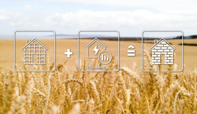 Picture of a grain field with an infographic in the foreground showing that the primary energy requirement for the construction of a conventional building consumes as much energy as a newly built straw house with a heat energy supply for the next 69 years.